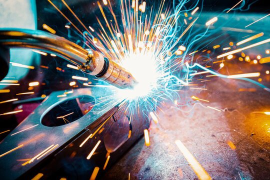 Close-up of a welder performing precision metal welding with sparks flying